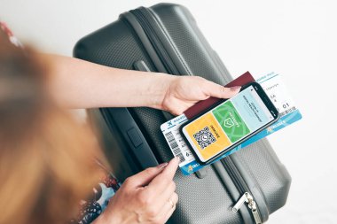Dijital covid sertifikası. Covid negatif hızlı dijital test geçişi. Cep telefonu, pasaport ve uçak biletinde dijital kimlik kartı olan bir kadın. Sayısal covid test sonuçlarını covid-19 p sırasında seyahat için tıbbi geçiş olarak gösteren gezgin