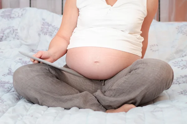 Gravid kvinde læser bog på en tablet - Stock-foto