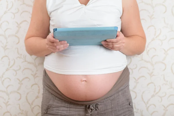 Mujer embarazada leyendo libro en una tableta — Foto de Stock