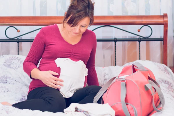 Gravid kvinna packning hospital bag förbereder för arbete Royaltyfria Stockbilder