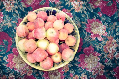 çiçekli masa örtüsü üzerinde kase meyve