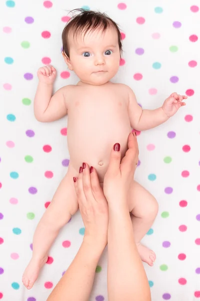 Pequena menina deitada em cobertor com bolinhas coloridas — Fotografia de Stock