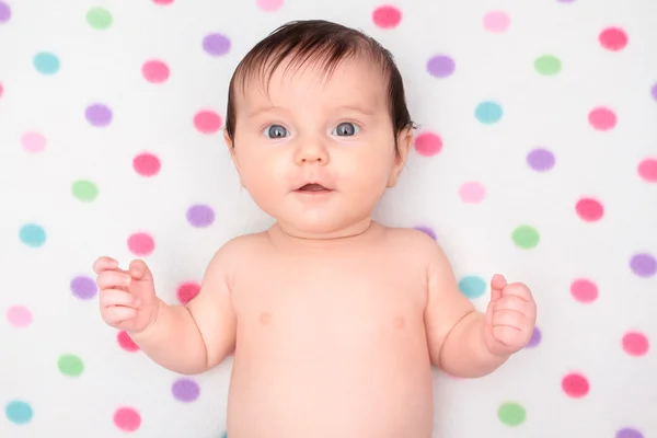 Little baby girl lying on blanket with colourful polka dots — Stock Photo, Image