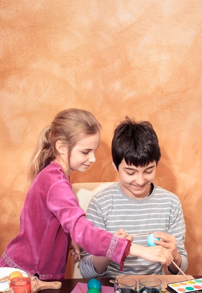 Sibling painting easter eggs at the table — Stock Photo, Image