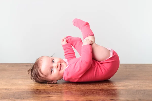 Smiling little baby girl playing with her feet — Stock Photo, Image