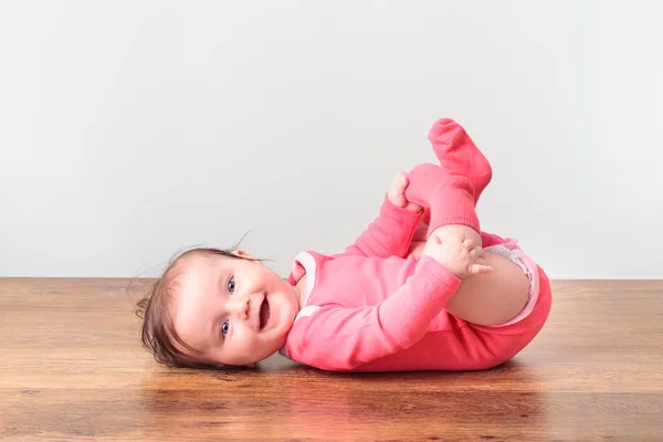 彼女の足で遊んで赤ちゃん少女の笑みを浮かべてください。 — ストック写真