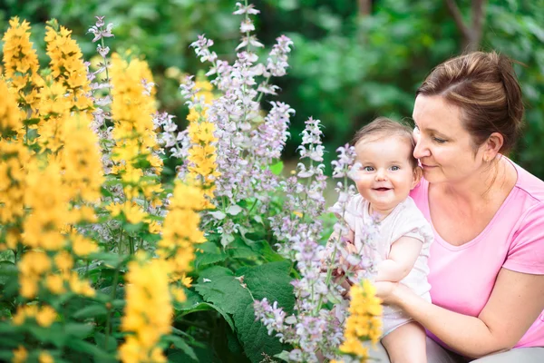 Matka, ukazující zahradní rostliny jí holčička — Stock fotografie
