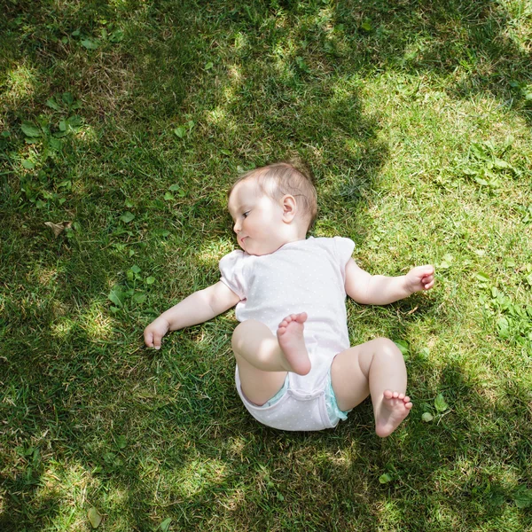Ребенок, лежащий на траве в саду — стоковое фото