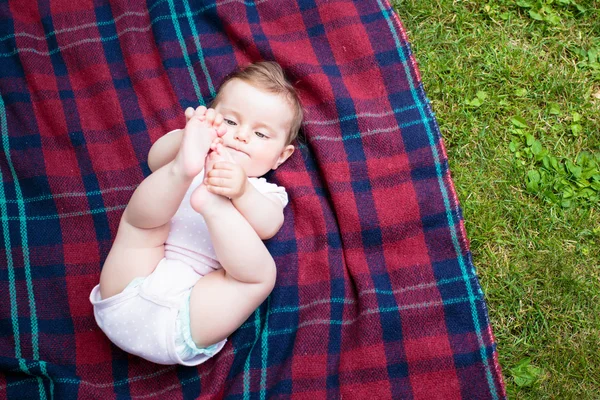 Baby lying on blanket in the garden — Stock Photo, Image