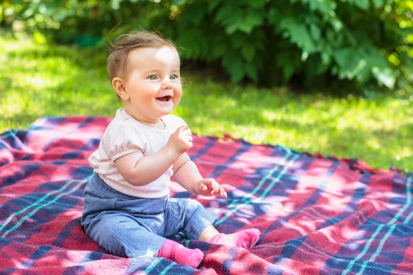 Baby sitting on a blanket in a garden — Stock Photo, Image