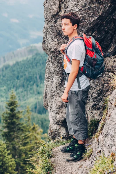 Мальчик, стоящий на скалах в горах — стоковое фото