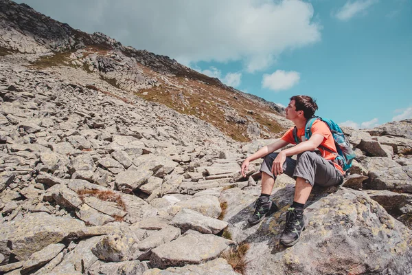 Boy resting on a rock in the mountains — Stock Photo, Image