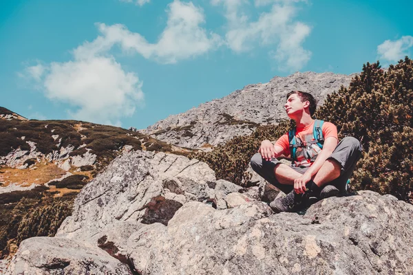 Garçon reposant sur un rocher dans les montagnes — Photo