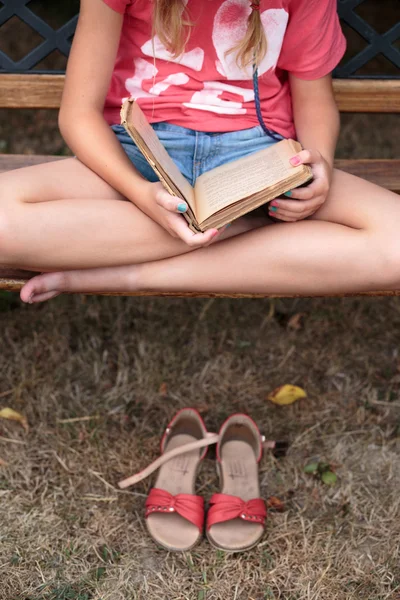 Meisje het lezen van een boek op een bankje — Stockfoto