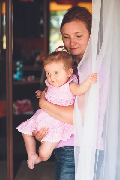 Vrouw stond op de patio deur met haar dochtertje op han — Stockfoto