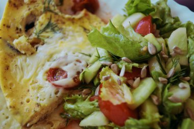 Taze sebzeli omlet ve salata tabakta leziz hafif kahvaltı makrosu fotoğraf arka planında.