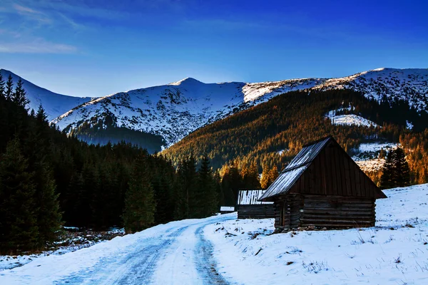 Besneeuwde berglandschap met houten huis onderdak — Stockfoto