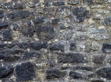 Geleneksel grungy Stone Duvarı. Kapatın. Harç ve düzensiz karartılmış taşları gösterin.