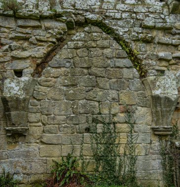 Yıpranmış kireç taşı işçiliğiyle ortaçağ manastırı kemeri