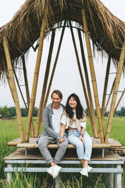 Birbirine aşık bir çift pirinç tarlasında bambu köprüsünde oturuyor.