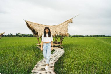 Kadın pirinç tarlasında bambu köprüsünde yürüyor.