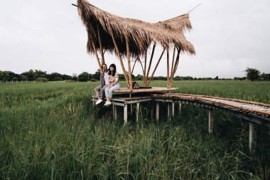 Birbirine aşık bir çift pirinç tarlasında bambu köprüsünde oturuyor.