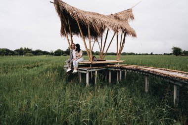Birbirine aşık bir çift pirinç tarlasında bambu köprüsünde oturuyor.