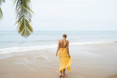 Tayland 'da kumsalda yürüyen mutlu bir kadın.