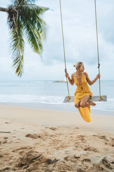 タイの花王ラックのビーチでスイング上の黄色のドレススイングの若い女性 — ストック写真