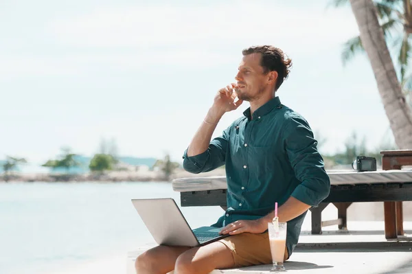 Man freelancer working with laptop at the beach in resort