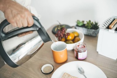 Adam evde çay yapıyor.