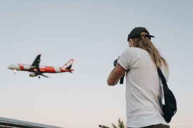 Sarışın adam gökyüzünde uçan uçak vuruyor.