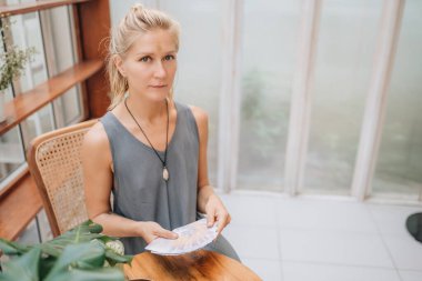 Kadın kafede masada Tarot kartları okuyor.