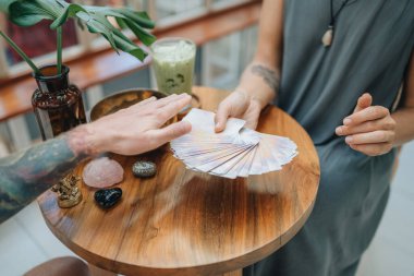 Kadın kafede Tarot kartları okuyor.