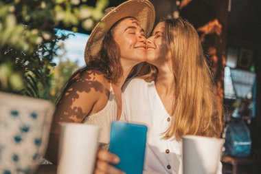 Kafede oturan ve akıllı telefondan video izleyen kadın çift.