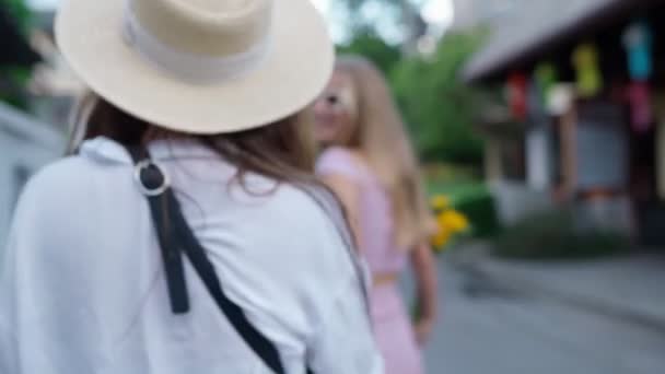 Zwei Freundinnen gehen auf der Straße spazieren. Verwackeltes defokussiertes Video. — Stockvideo
