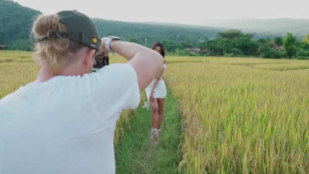 Mann fotografiert junge Thailänderin in Reisfeld — Stockvideo