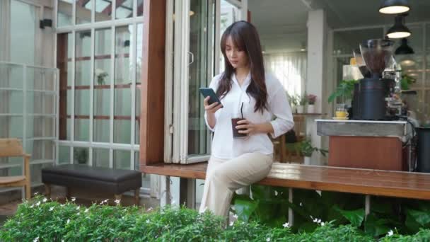Thailänderin sitzt im Café und chattet mit ihrem Handy — Stockvideo