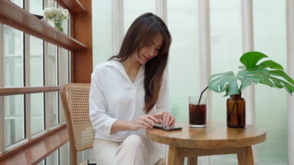 Mulher tailandesa sentada no café e conversando em seu telefone — Vídeo de Stock