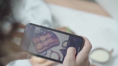 Kadın eli, modern akıllı telefonla yiyeceklerin fotoğrafını çeker. - Yakın çekim. 4K.