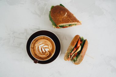 Bir fincan kahve ve panini bembeyaz masanın üstünde.