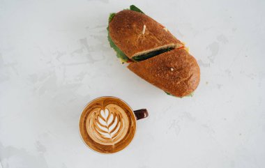 Bir fincan kahve ve panini bembeyaz masanın üstünde.