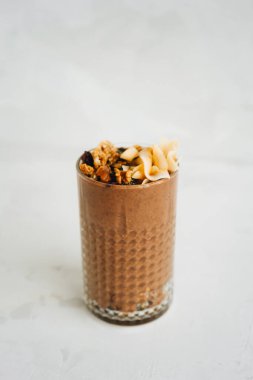 Beyaz arka planda bir bardak kahverengi smoothie..