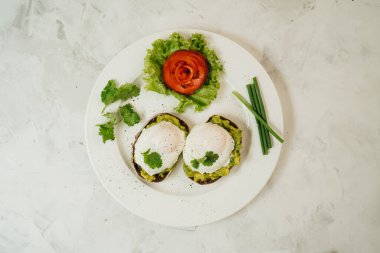 Beyaz arka planda kızarmış ekşi ekmek ve avokado ile haşlanmış yumurta. Üst görünüm