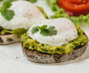 Beyaz arka planda kızarmış ekşi ekmek ve avokado ile haşlanmış yumurta. Tside görünümü