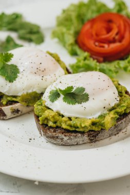 Beyaz arka planda kızarmış ekşi ekmek ve avokado ile haşlanmış yumurta. Tside görünümü