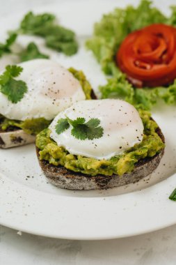 Beyaz arka planda kızarmış ekşi ekmek ve avokado ile haşlanmış yumurta. Tside görünümü