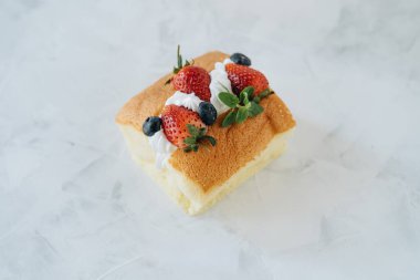 Krem şantili bisküvi ve beyaz arka planda çilek.