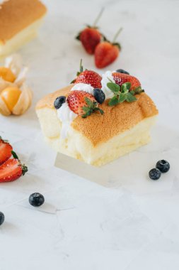 Krem şantili bisküvi ve beyaz arka planda çilek.