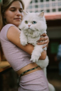 Dışarıda kediyi tutan şapkalı gülen bir kadın.